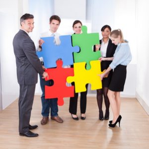 High Angle View Of Businesspeople Holding Multi Colored Jigsaw Puzzle